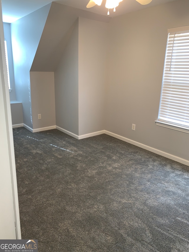 bonus room featuring ceiling fan, lofted ceiling, and dark colored carpet