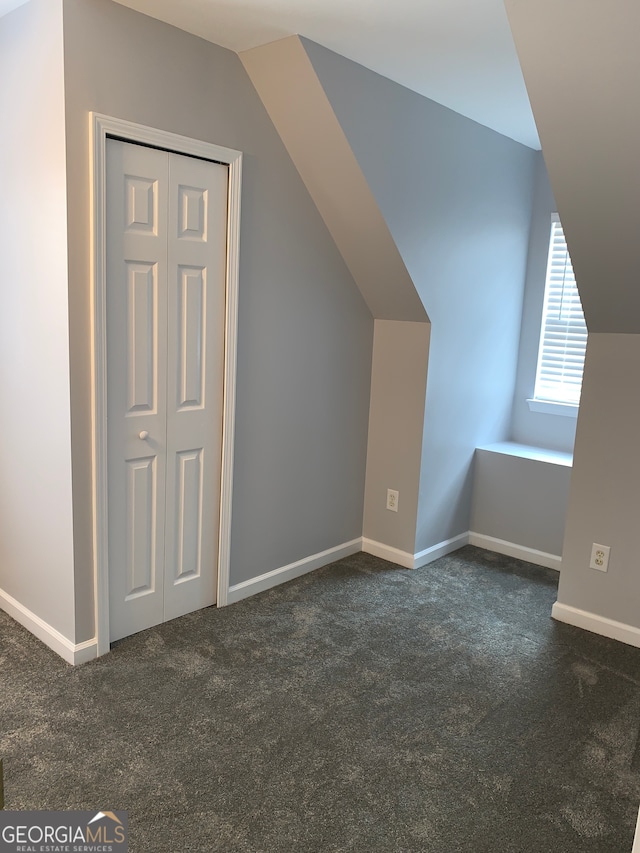 additional living space featuring dark carpet and lofted ceiling