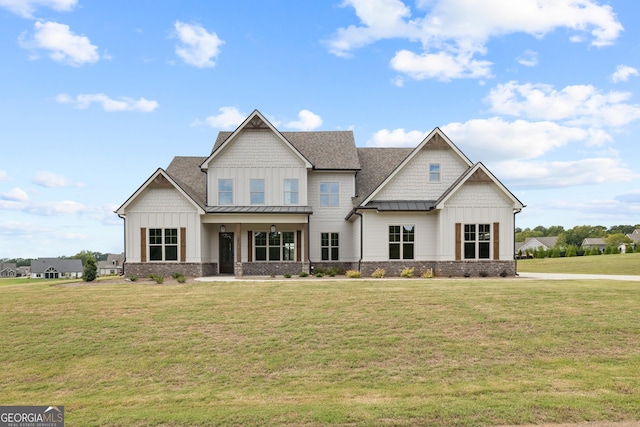 view of front facade featuring a front yard, a standing seam roof, brick siding, a shingled roof, and board and batten siding