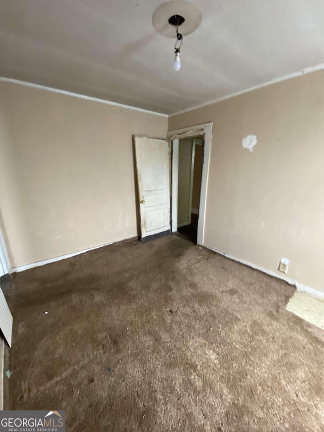 spare room featuring crown molding and carpet flooring