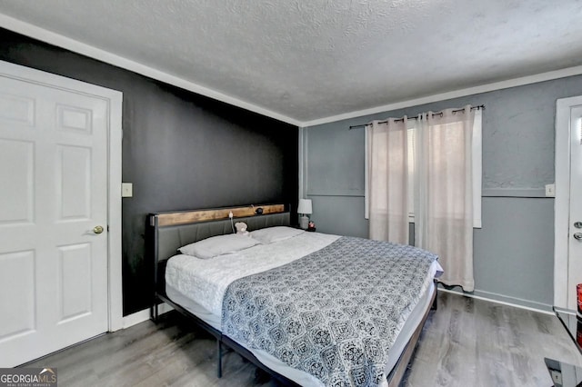 bedroom with a textured ceiling, crown molding, and wood-type flooring