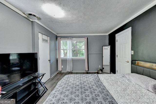 bedroom featuring hardwood / wood-style flooring, ornamental molding, and a textured ceiling