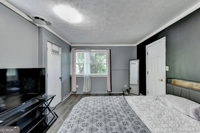 bedroom featuring crown molding, wood-type flooring, and a textured ceiling