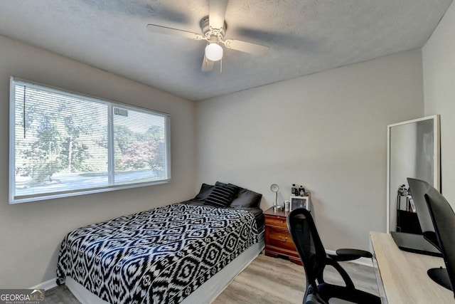 bedroom featuring ceiling fan, hardwood / wood-style flooring, and a textured ceiling