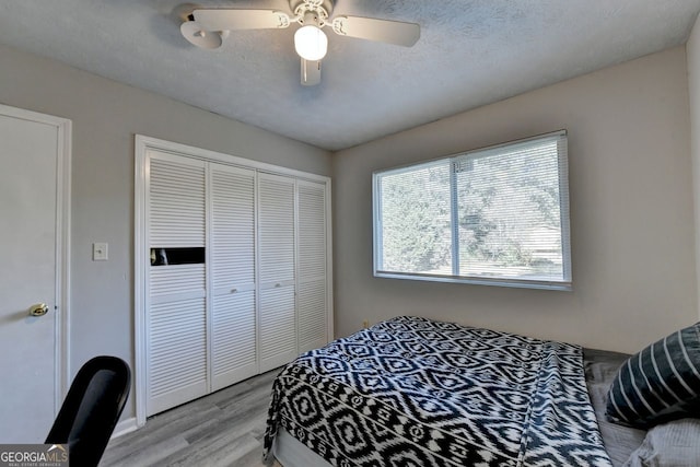 bedroom featuring a closet, a textured ceiling, light wood-type flooring, and ceiling fan