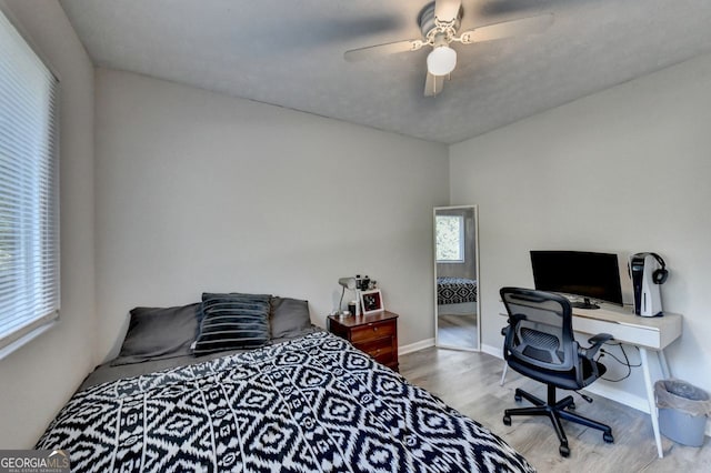 bedroom with a textured ceiling, light wood-type flooring, and ceiling fan