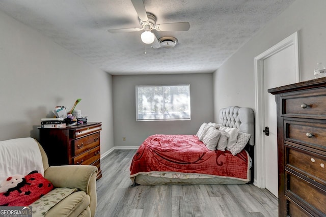 bedroom with a textured ceiling, light wood-type flooring, and ceiling fan