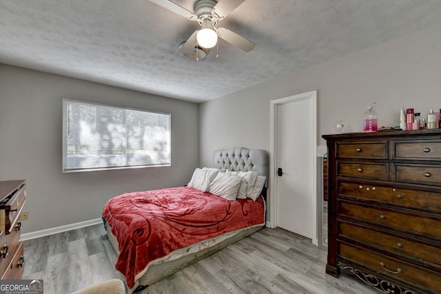 bedroom featuring a textured ceiling, light wood-type flooring, and ceiling fan