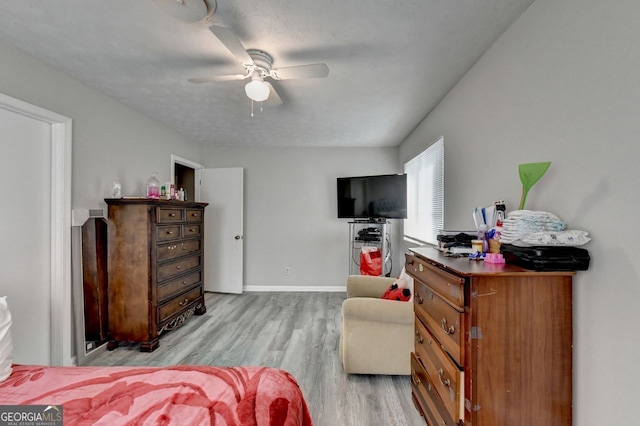 bedroom with light hardwood / wood-style flooring, a textured ceiling, and ceiling fan