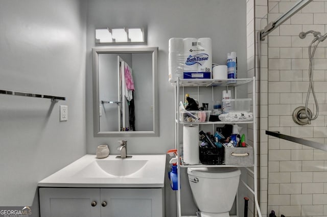 bathroom with vanity, tiled shower, and toilet