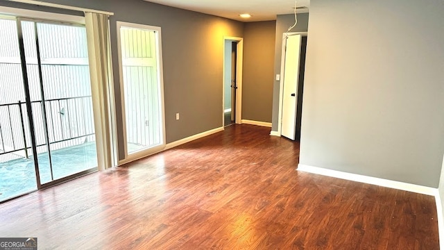 empty room with dark hardwood / wood-style flooring and a wealth of natural light