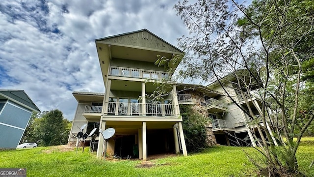 rear view of house featuring a balcony and a yard