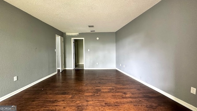 unfurnished room featuring a textured ceiling and dark hardwood / wood-style flooring