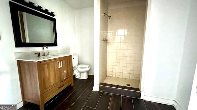 bathroom featuring tiled shower, vanity, and toilet