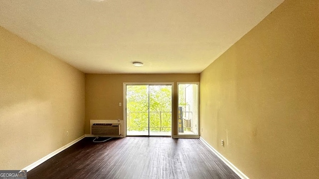 empty room with dark hardwood / wood-style flooring and an AC wall unit