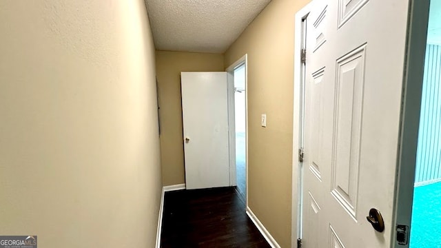 hall featuring a textured ceiling and dark wood-type flooring