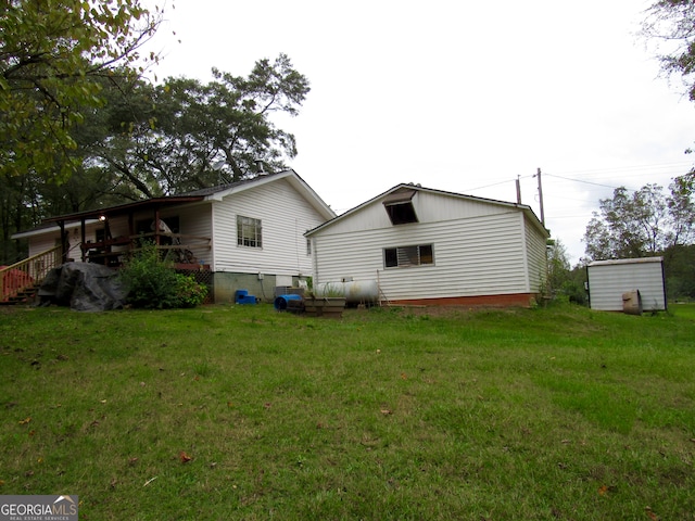 back of house with a shed and a yard