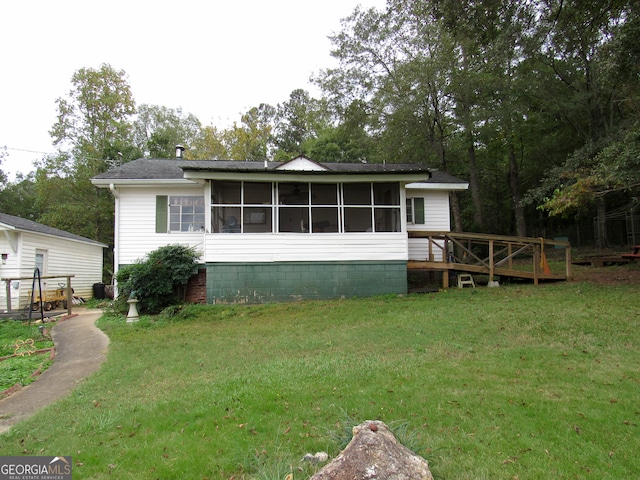 back of property with a lawn, a deck, and a sunroom