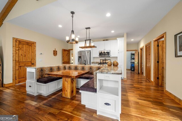 kitchen featuring hardwood / wood-style floors, pendant lighting, stainless steel appliances, and white cabinets