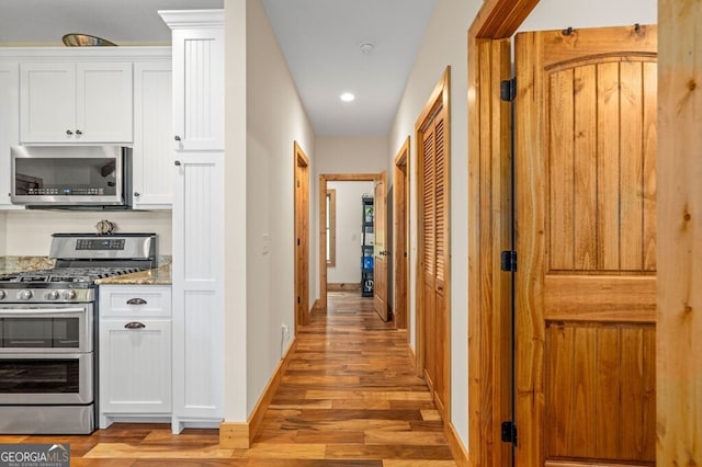 292 Silver Fox Trl, Blue Ridge, GA 30513 - kitchen with stainless steel appliances, white cabinets, light wood-type flooring, baseboards, and light stone counters