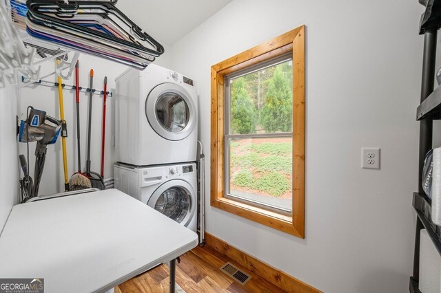 washroom featuring stacked washer / dryer and hardwood / wood-style flooring