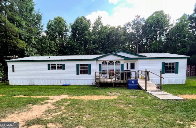 back of property featuring a wooden deck and a yard