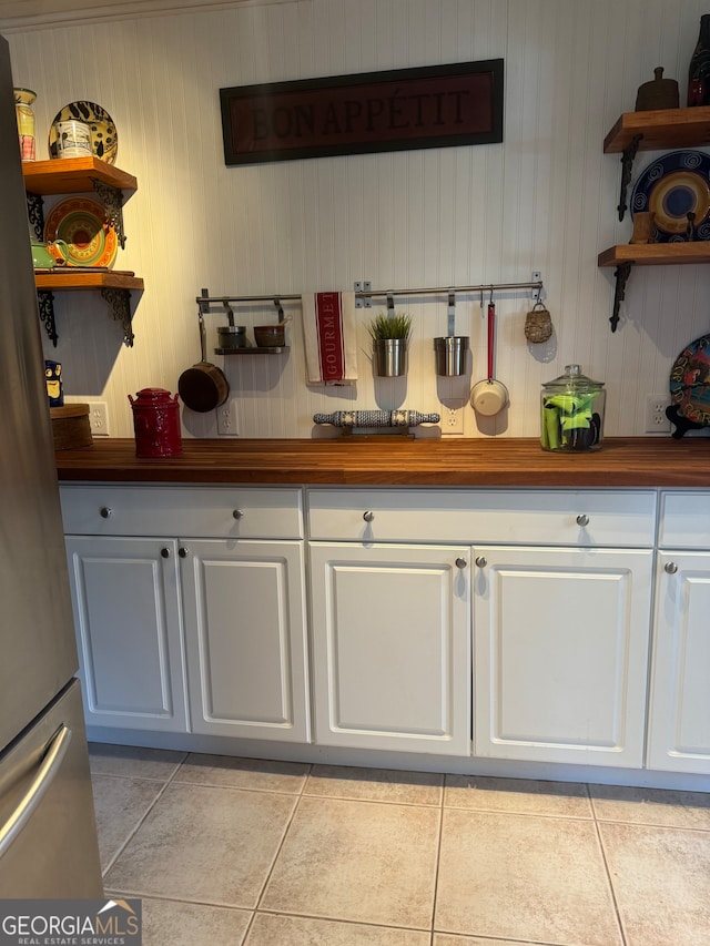 kitchen featuring white cabinets, stainless steel fridge, and light tile patterned floors