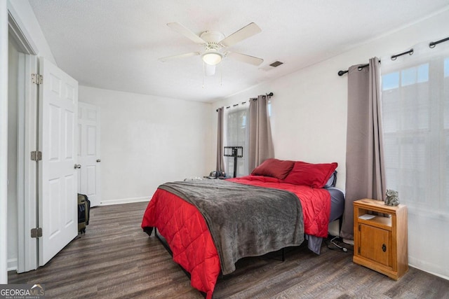 bedroom with multiple windows, ceiling fan, and dark wood-type flooring