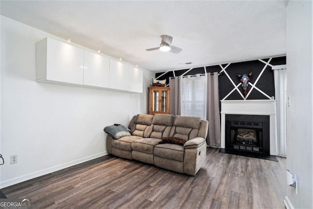 living room with a textured ceiling, ceiling fan, and dark hardwood / wood-style flooring