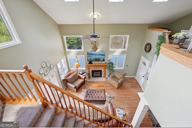 living room with ceiling fan, hardwood / wood-style flooring, and a tile fireplace