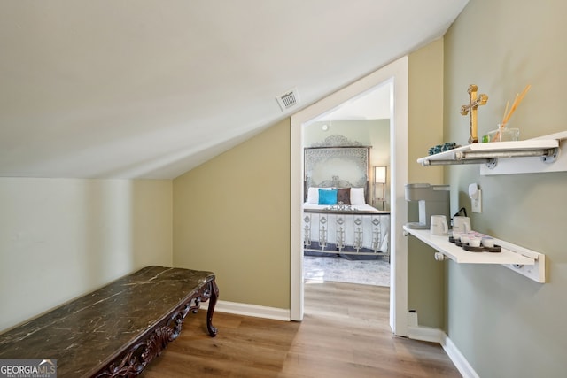 hallway with lofted ceiling and hardwood / wood-style floors