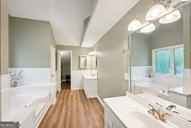 bathroom with vanity, lofted ceiling, a washtub, and hardwood / wood-style flooring