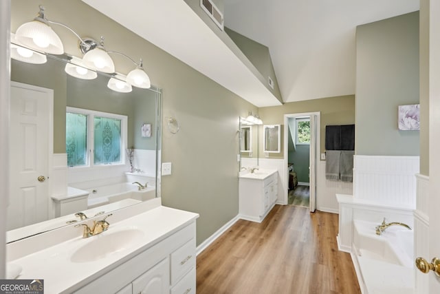 bathroom with wood-type flooring, vanity, a tub, and vaulted ceiling