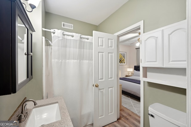 bathroom featuring ceiling fan, sink, hardwood / wood-style flooring, walk in shower, and toilet