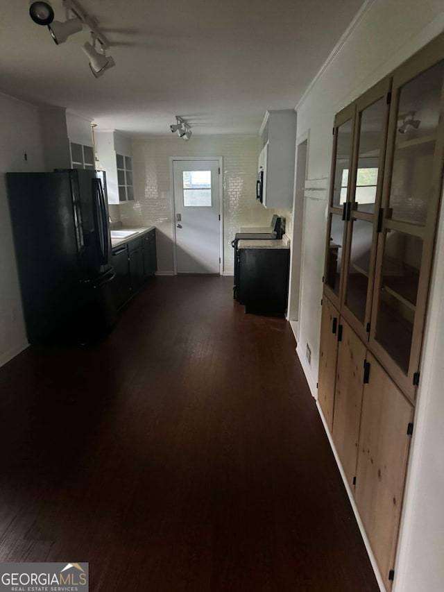 interior space with rail lighting, dark wood-type flooring, and crown molding