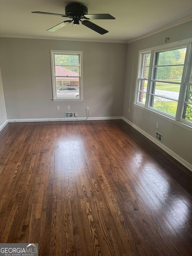 unfurnished room with ornamental molding, a wealth of natural light, ceiling fan, and dark wood-type flooring