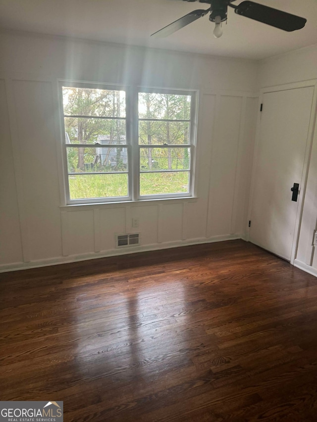 empty room with ceiling fan and dark hardwood / wood-style flooring