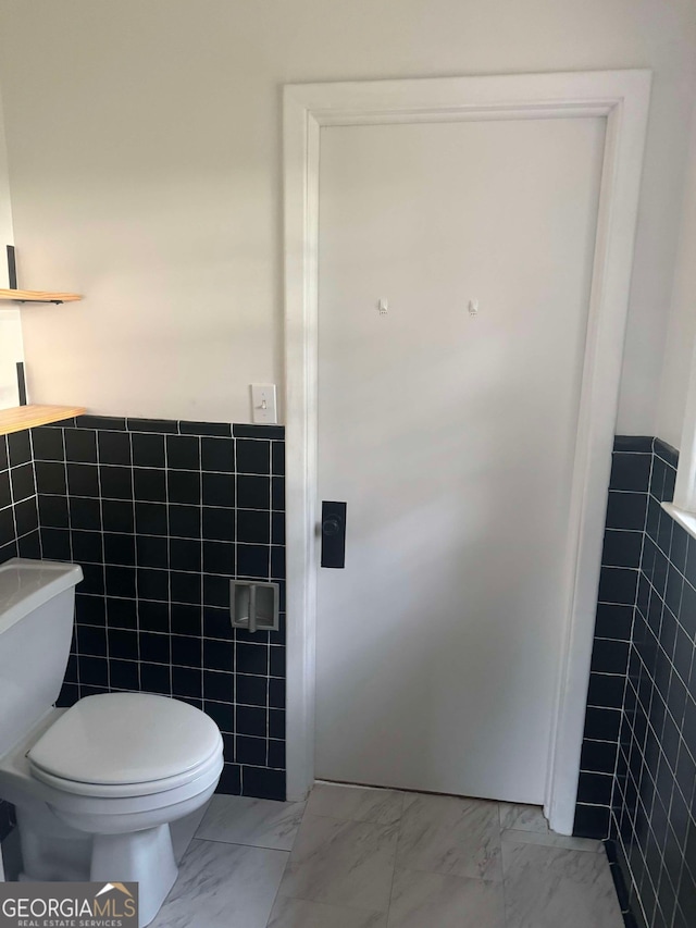 bathroom featuring tile walls and toilet