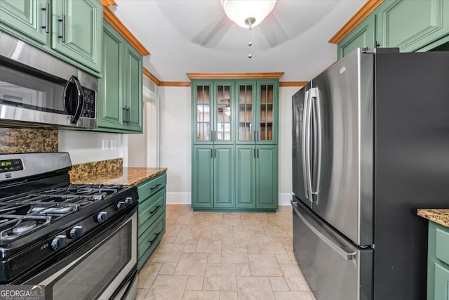 kitchen featuring appliances with stainless steel finishes, light stone counters, green cabinetry, crown molding, and ceiling fan