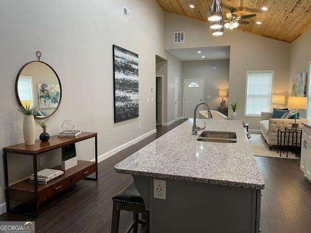 kitchen with an island with sink, dark hardwood / wood-style flooring, high vaulted ceiling, and wooden ceiling