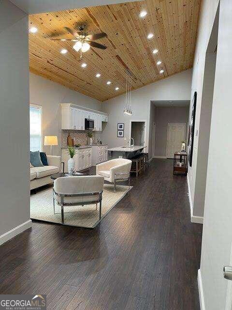 living room featuring wood ceiling, dark hardwood / wood-style floors, ceiling fan, and high vaulted ceiling