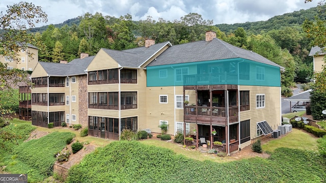 exterior space with a balcony, central AC unit, and a yard