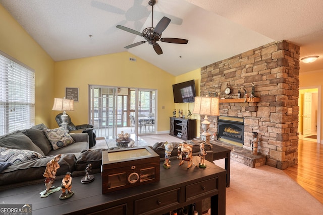 living room with light hardwood / wood-style floors, vaulted ceiling, a fireplace, a textured ceiling, and ceiling fan