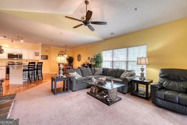 living room with light hardwood / wood-style floors, a textured ceiling, lofted ceiling, ceiling fan, and ornamental molding