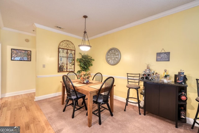 dining area with a textured ceiling, light hardwood / wood-style floors, and crown molding