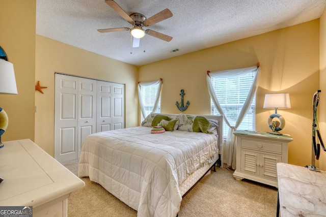 carpeted bedroom featuring a textured ceiling, ceiling fan, and a closet