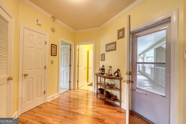 doorway with light wood-type flooring, a textured ceiling, and crown molding