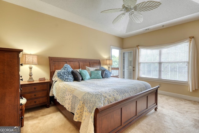 bedroom with ceiling fan, light colored carpet, and a textured ceiling