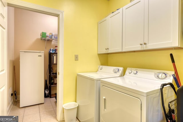 washroom featuring cabinets, washing machine and clothes dryer, and light tile patterned flooring