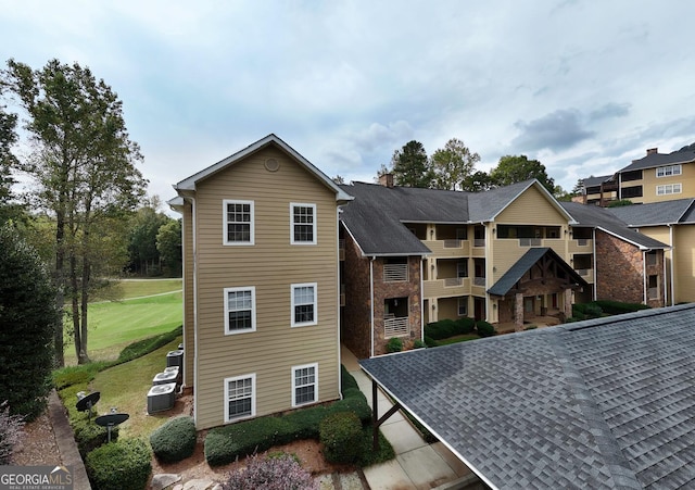 view of front of house with a balcony, a front lawn, and central AC unit